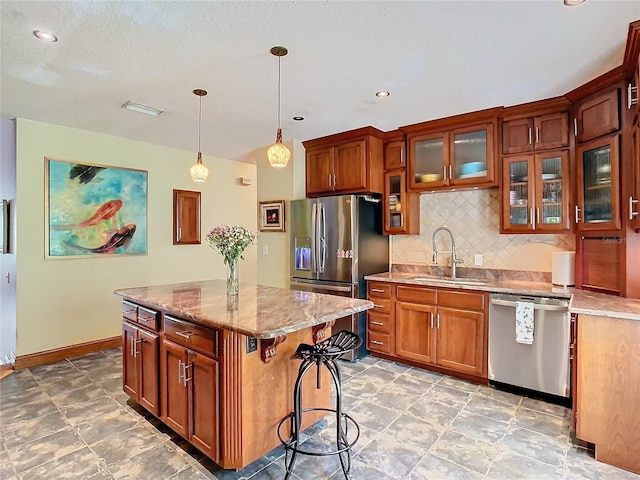 kitchen with a kitchen island, appliances with stainless steel finishes, decorative light fixtures, sink, and decorative backsplash