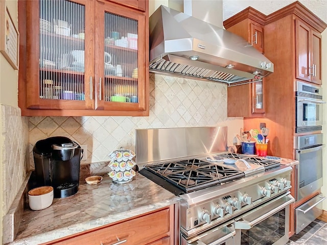 kitchen featuring stainless steel range, light stone countertops, extractor fan, and backsplash