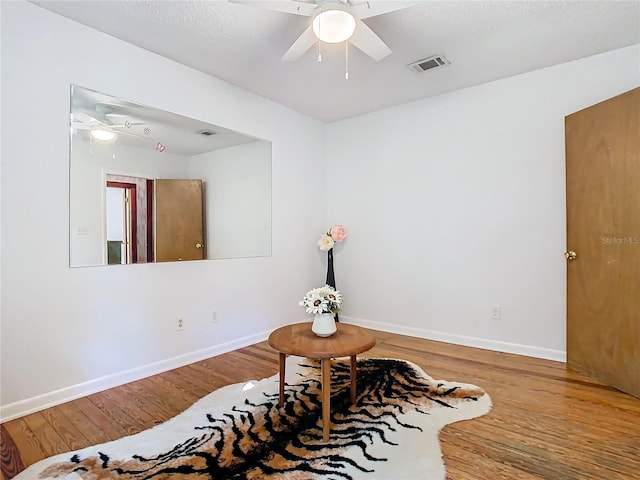 living area featuring hardwood / wood-style flooring and ceiling fan