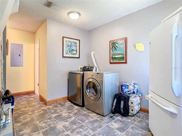 laundry room with independent washer and dryer, electric panel, and a textured ceiling