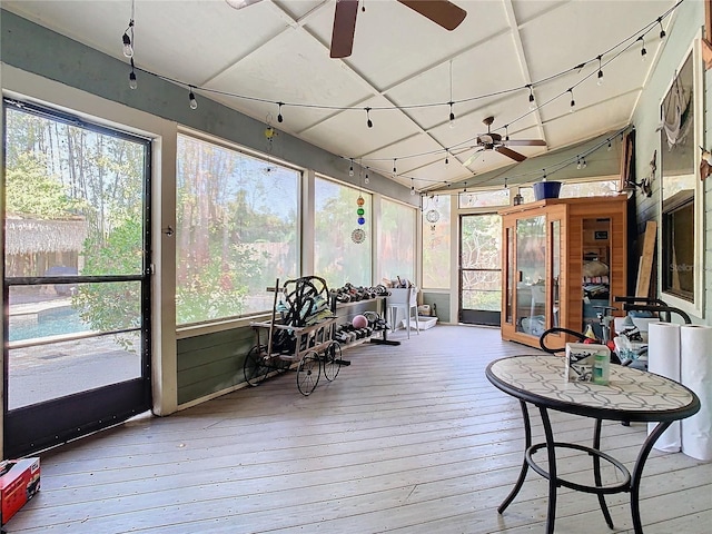 sunroom / solarium featuring vaulted ceiling, plenty of natural light, track lighting, and ceiling fan