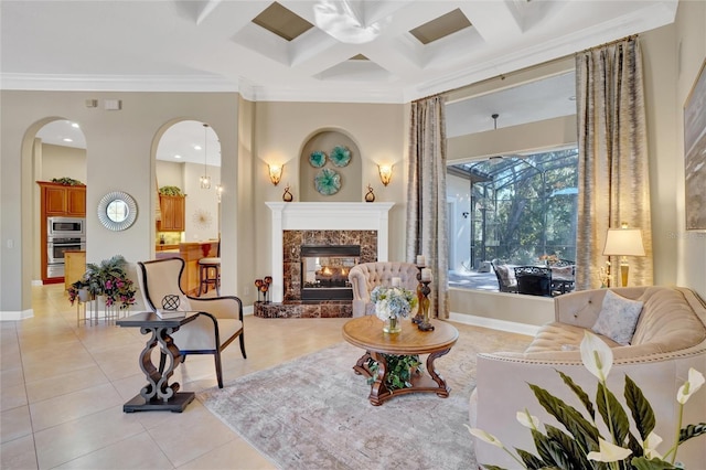 living area featuring coffered ceiling, light tile patterned floors, crown molding, and a fireplace