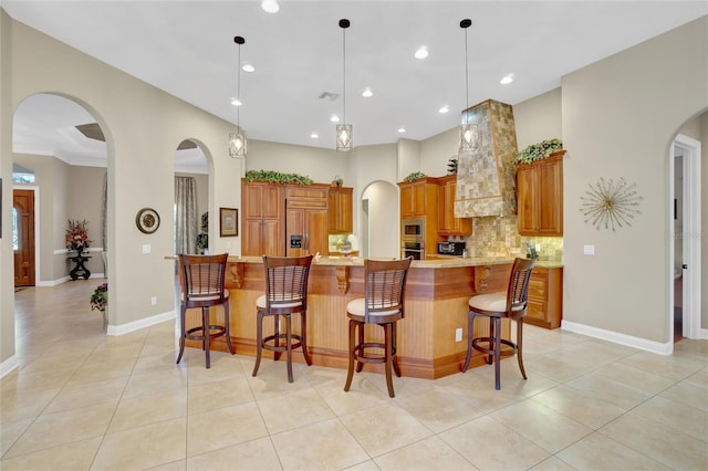 kitchen featuring a breakfast bar area, tasteful backsplash, built in appliances, pendant lighting, and a large island