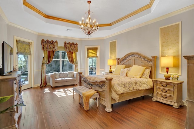 bedroom with a tray ceiling, a chandelier, and hardwood / wood-style floors