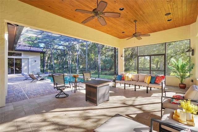 view of patio featuring outdoor lounge area, ceiling fan, and glass enclosure