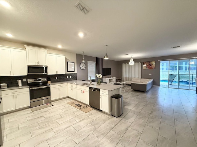 kitchen featuring decorative light fixtures, stainless steel appliances, kitchen peninsula, and white cabinets