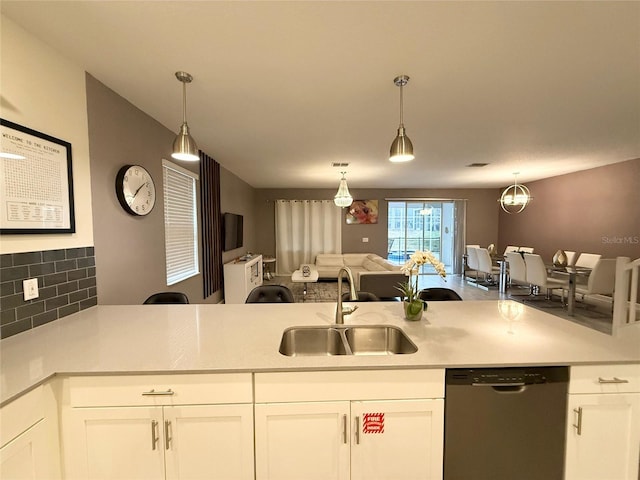 kitchen with stainless steel dishwasher, decorative light fixtures, sink, and white cabinets