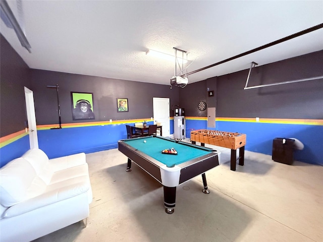 playroom featuring water heater, pool table, concrete floors, and a textured ceiling