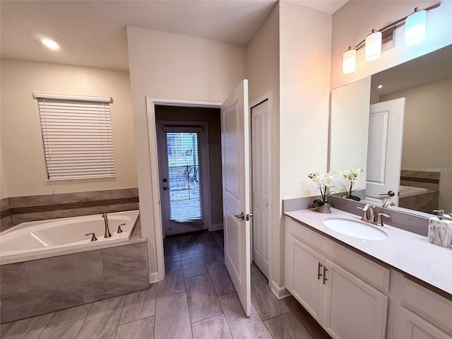 bathroom with vanity and a relaxing tiled tub