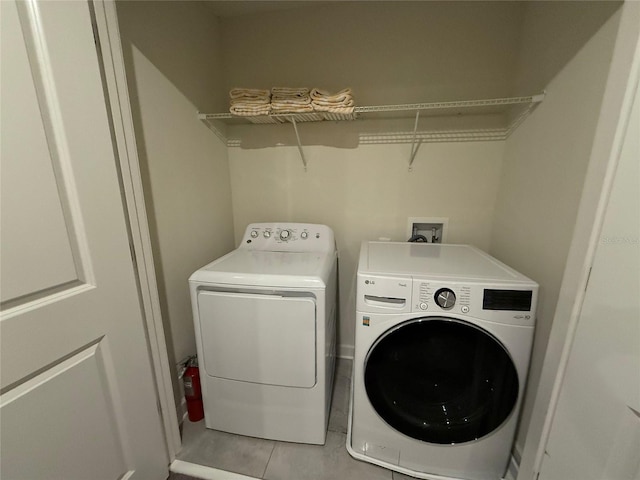 clothes washing area featuring washer and dryer and light tile patterned flooring