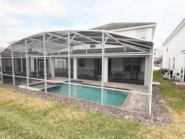 rear view of property with a pool with hot tub, glass enclosure, and a patio area