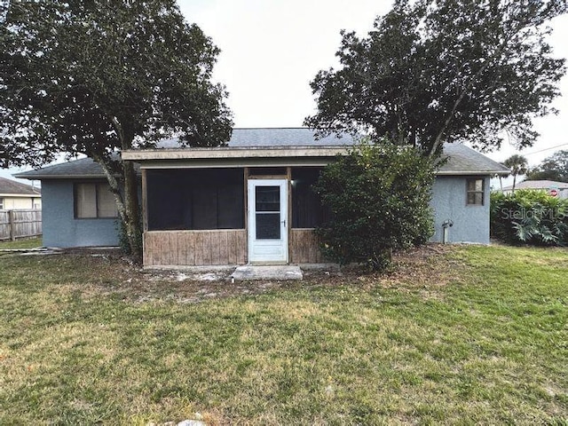 rear view of property featuring a sunroom and a yard