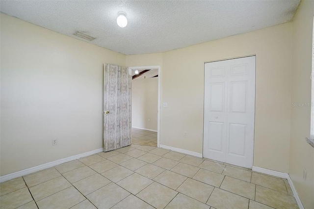 unfurnished bedroom featuring light tile patterned floors, a closet, and a textured ceiling