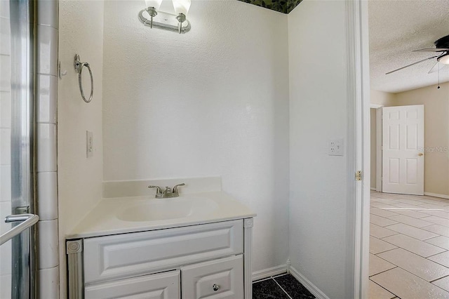 bathroom with ceiling fan, vanity, tile patterned flooring, and a textured ceiling