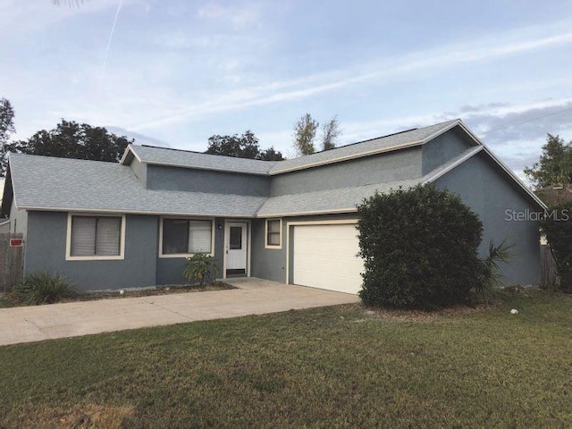 single story home with stucco siding, an attached garage, a front lawn, and driveway