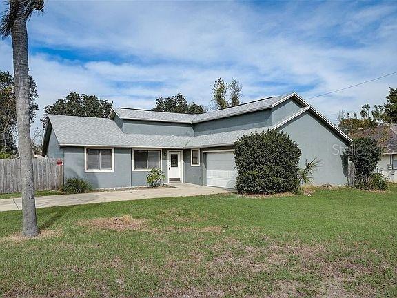 ranch-style house featuring an attached garage, stucco siding, fence, concrete driveway, and a front yard