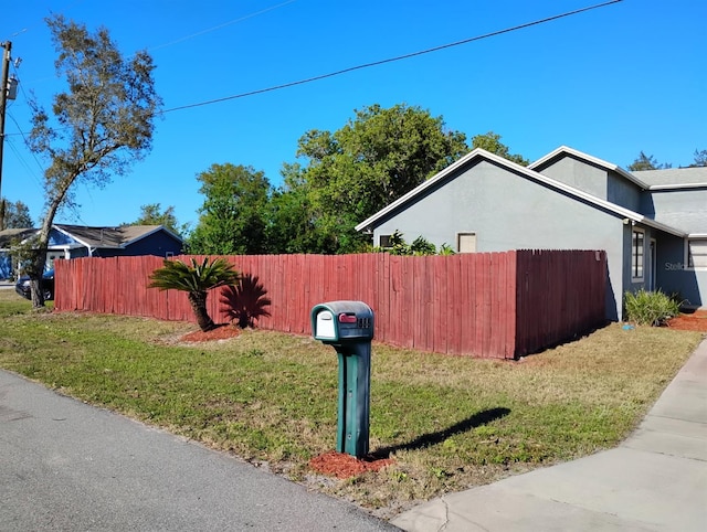 view of property exterior with a lawn, stucco siding, and fence