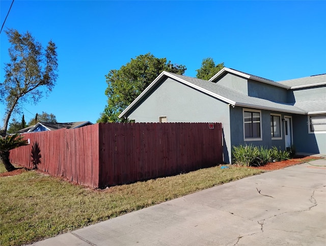 view of property exterior featuring a yard, stucco siding, and fence