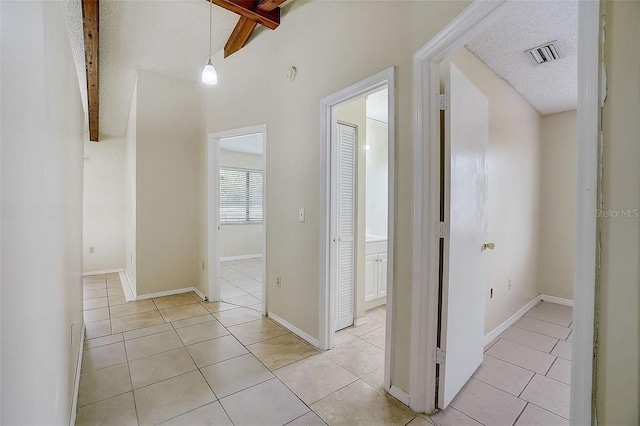 corridor featuring a textured ceiling, beamed ceiling, visible vents, and light tile patterned flooring
