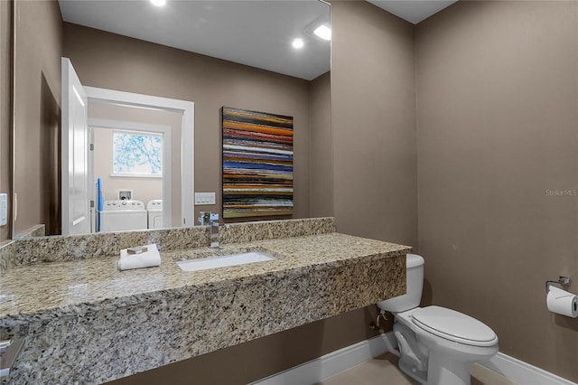 bathroom featuring washing machine and clothes dryer, toilet, and sink