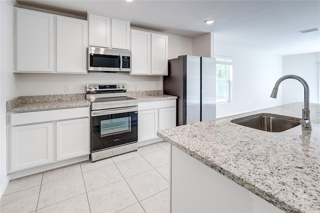 kitchen with appliances with stainless steel finishes, sink, white cabinets, and light stone counters