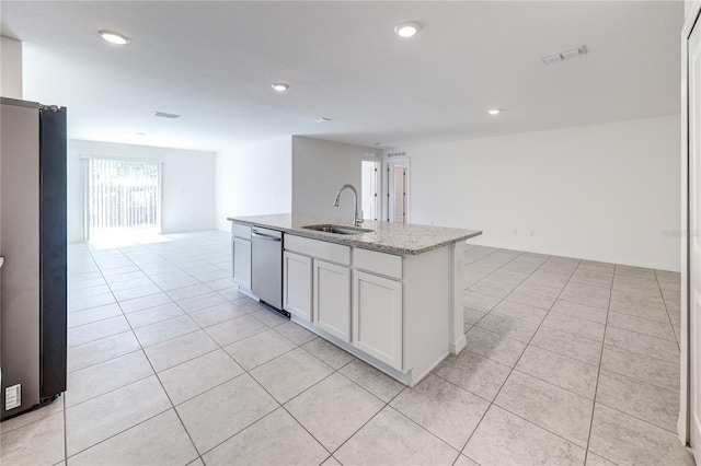 kitchen with sink, appliances with stainless steel finishes, white cabinetry, light stone counters, and an island with sink