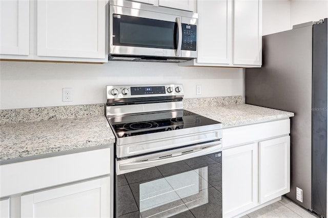 kitchen featuring white cabinetry, appliances with stainless steel finishes, light stone countertops, and light tile patterned floors