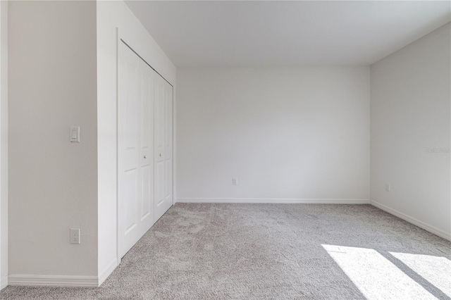 unfurnished bedroom with light colored carpet and a closet