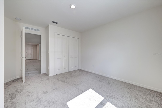 unfurnished bedroom with light colored carpet and a closet