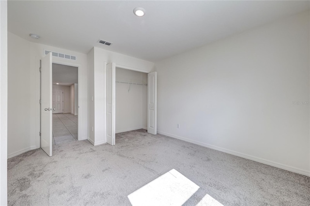 unfurnished bedroom featuring light colored carpet and a closet