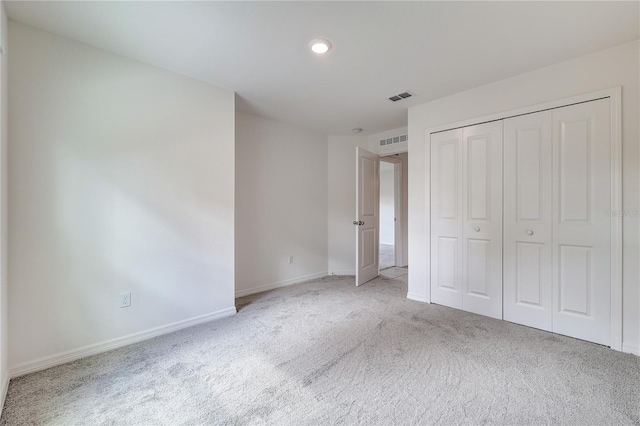 unfurnished bedroom with light carpet and a closet