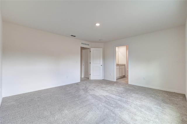 unfurnished bedroom featuring connected bathroom and light carpet