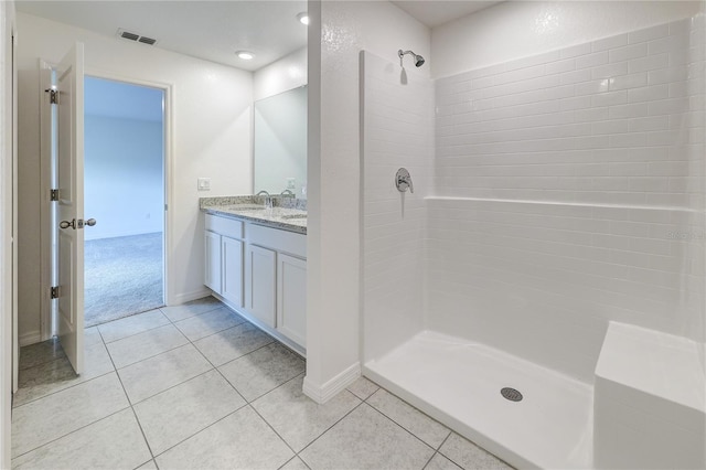 bathroom with walk in shower, vanity, and tile patterned flooring