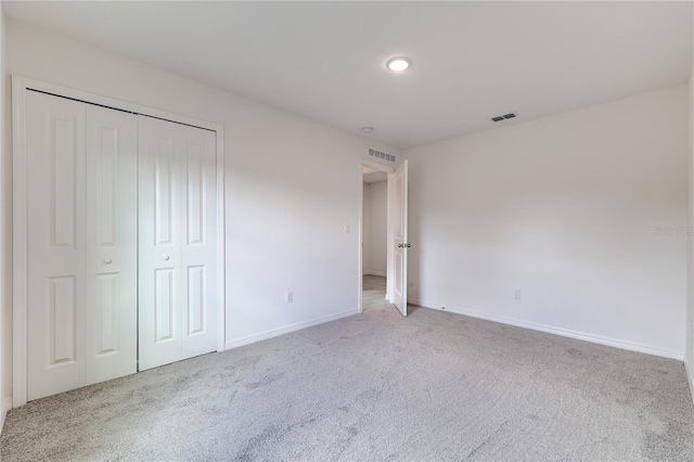 unfurnished bedroom featuring light colored carpet and a closet