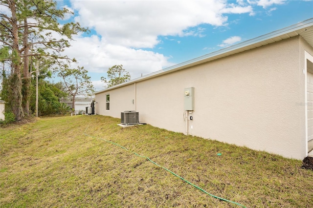 view of side of property with a yard and central AC unit