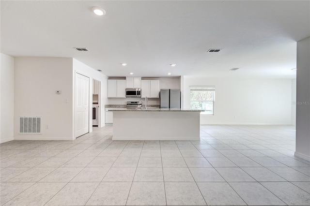 kitchen featuring white cabinetry, stainless steel appliances, light tile patterned flooring, and light stone counters