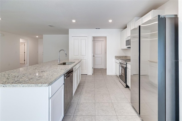 kitchen with sink, appliances with stainless steel finishes, a kitchen island with sink, white cabinetry, and light stone countertops