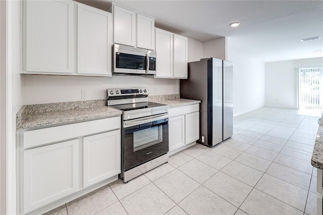 kitchen with white cabinetry, stainless steel appliances, light stone counters, and light tile patterned floors