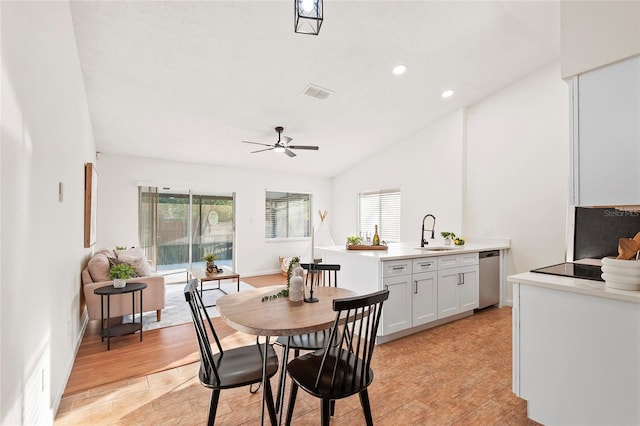 dining area featuring vaulted ceiling, ceiling fan, sink, and light hardwood / wood-style flooring