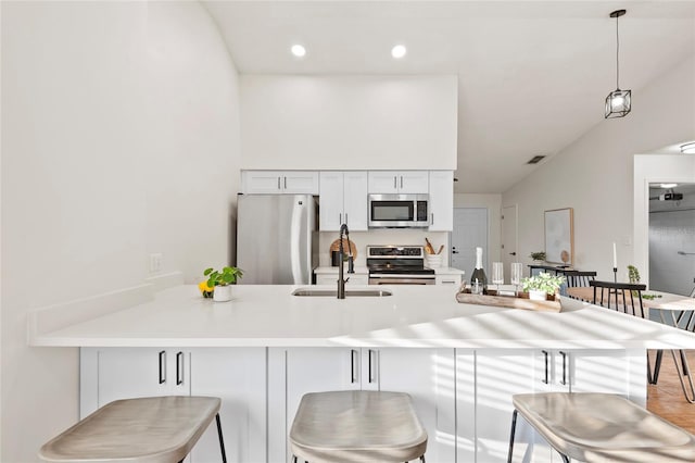 kitchen featuring a breakfast bar, white cabinetry, kitchen peninsula, pendant lighting, and stainless steel appliances