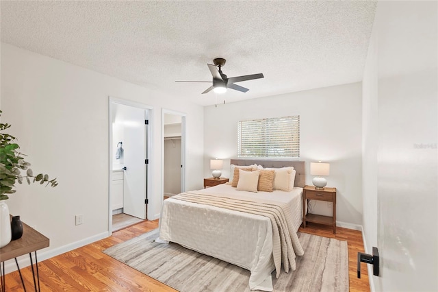 bedroom with a spacious closet, a textured ceiling, light wood-type flooring, a closet, and ceiling fan