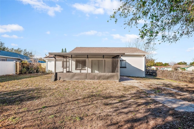 rear view of property with a sunroom and a lawn