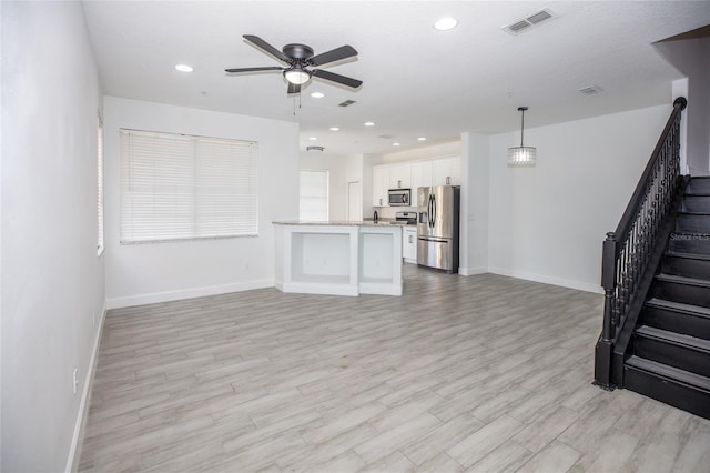 unfurnished living room with ceiling fan and light hardwood / wood-style flooring