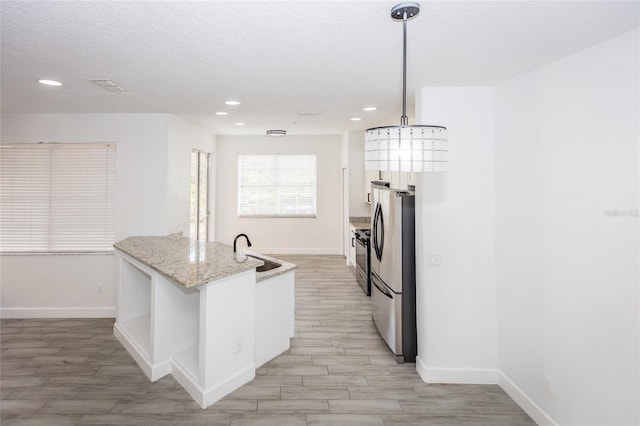 kitchen featuring sink, white cabinetry, appliances with stainless steel finishes, pendant lighting, and light stone countertops