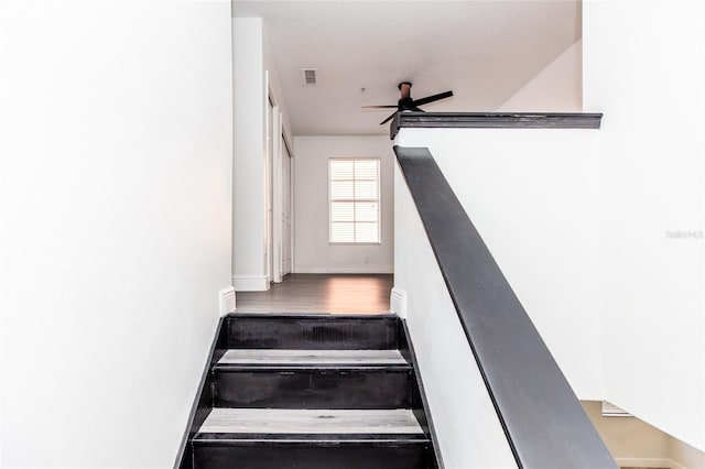 stairway with wood-type flooring and ceiling fan