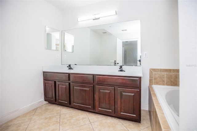 bathroom with tile patterned floors, vanity, and tiled tub