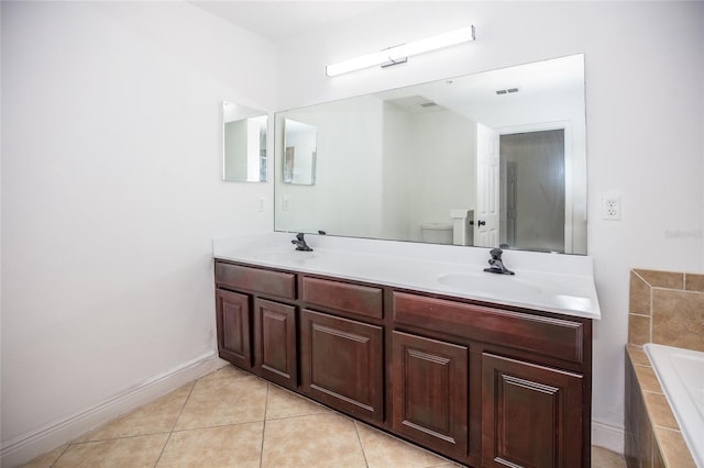 bathroom featuring tile patterned flooring, vanity, tiled bath, and toilet