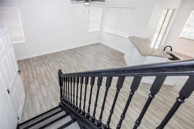 staircase with wood-type flooring and ceiling fan