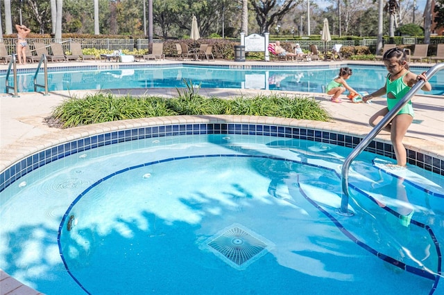 view of swimming pool with a hot tub