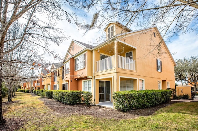 rear view of property with a balcony and a lawn